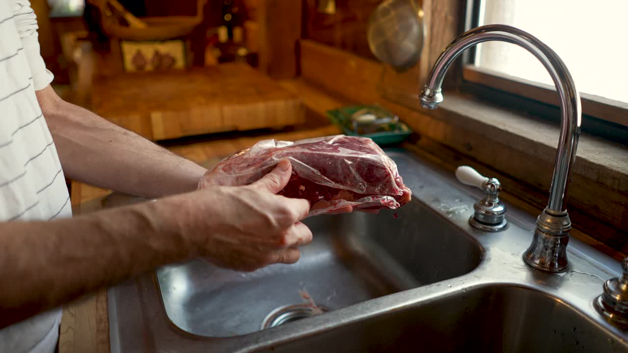 一名男子从塑料包装中取出一块烤牛肉，并将其展示给摄像机视频下载