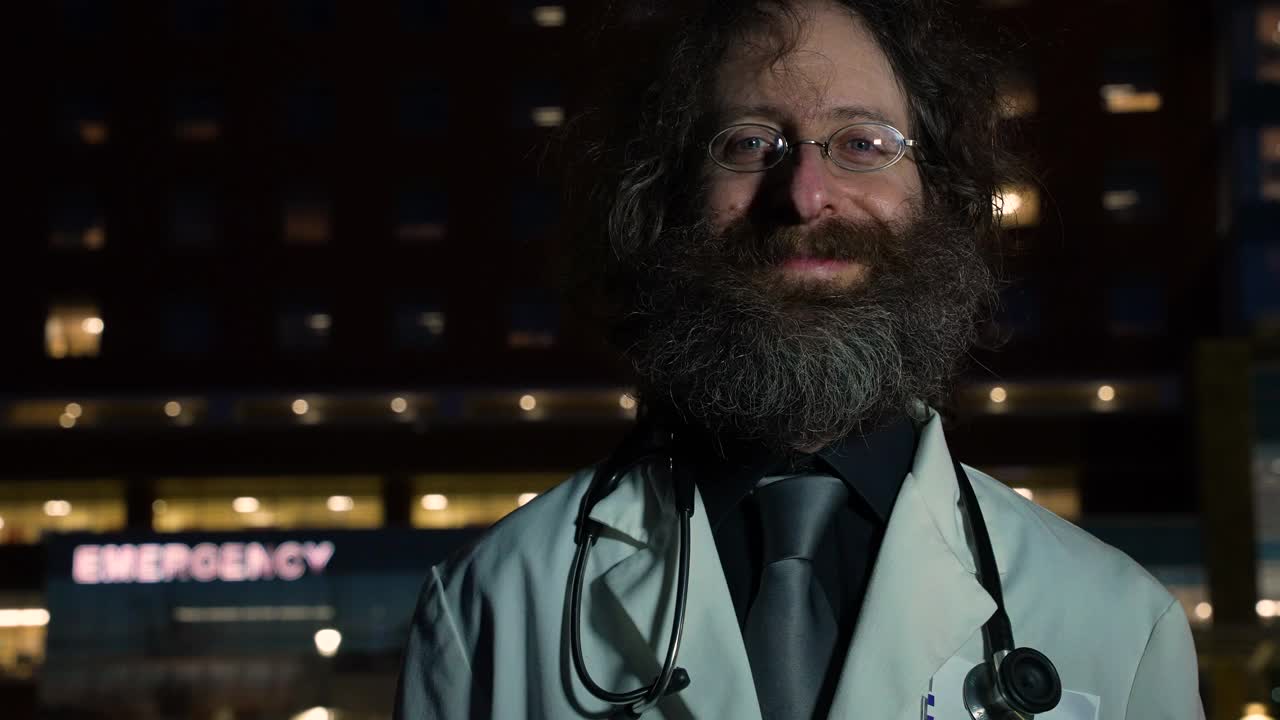 微笑的医生看着摄像机在医院前的夜晚视频下载