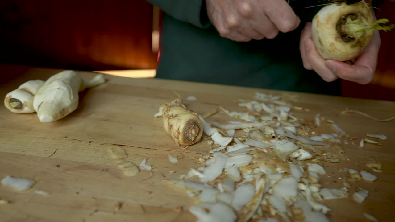 一名男子正在用蔬菜削皮器剥欧洲防风根菜的皮视频下载