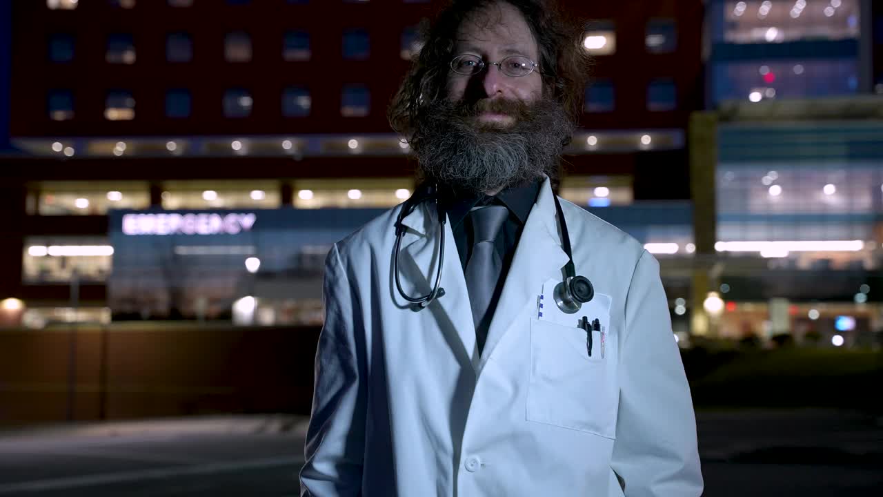 一个男医生晚上在医院外竖起两个大拇指的肖像视频下载