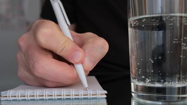 男人的手用圆珠笔在笔记本上写东西。视频素材