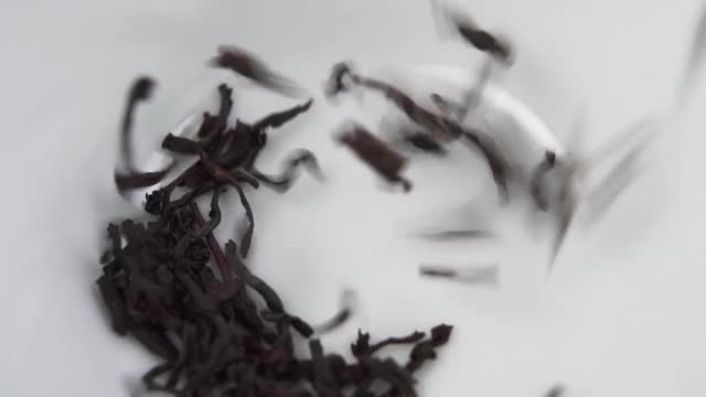 干红茶叶子落在白色陶瓷茶杯的底部视频下载