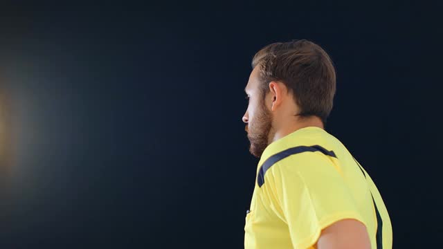 足球足球裁判在黑色背景上显示罚球红牌，4k慢动作视频素材