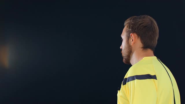 足球足球裁判在黑色背景上显示点球红牌，4k视频素材