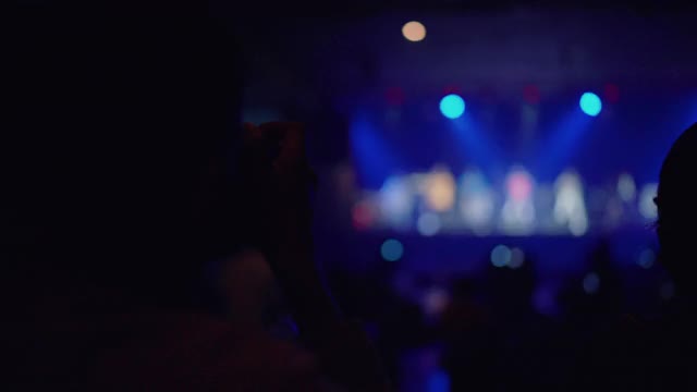 亚洲乐队在舞台上表演时，一名男子用相机记录音乐会。视频素材