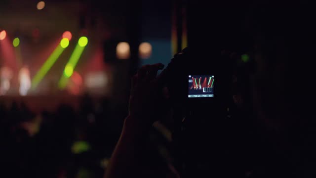 亚洲乐队在舞台上表演时，一名男子用相机记录音乐会。视频素材