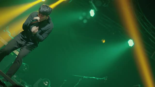 亚洲男歌手拿着麦克风在音乐厅的舞台上表演。视频素材