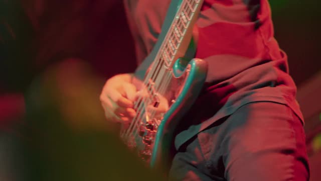 亚洲男子吉他手表演在夜总会的舞台上与摇滚乐队。视频素材