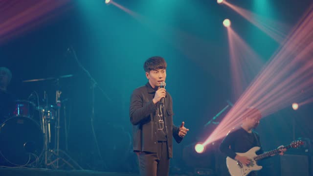 亚洲男歌手拿着麦克风在音乐厅的舞台上表演。视频素材