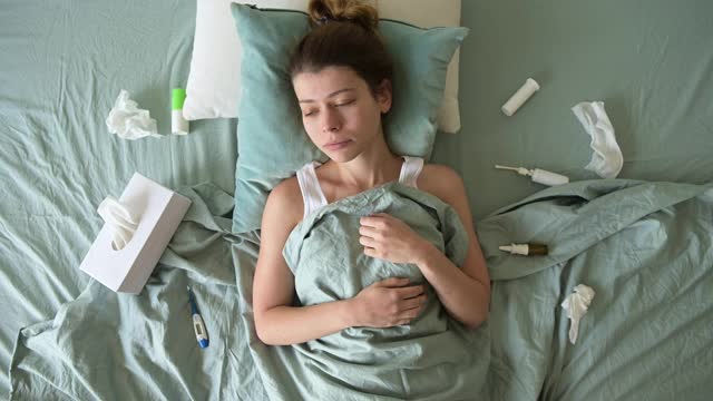一个病恹恹的年轻女子躺在床上受苦。药物到处都是视频素材