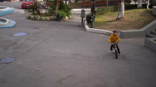 小男孩在公园的水泥地上骑自行车视频素材