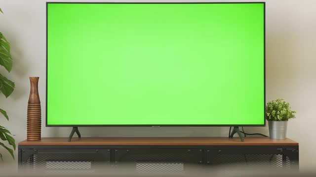 缩小镜头的电视绿色屏幕在客厅与树和灯。彩色键屏幕为广告。视频下载