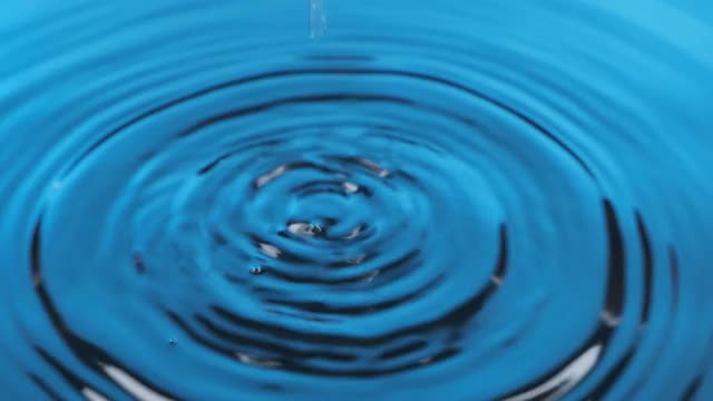 一滴水滴在蓝色的水中的缩放。美丽的圆波，波纹。视频下载