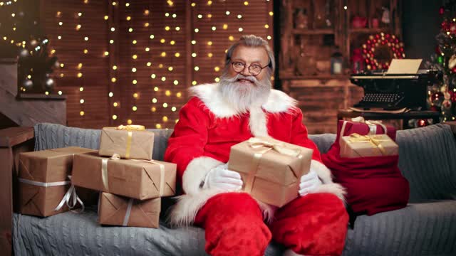 快乐的圣诞老人与包装好的圣诞礼物盒。用RED摄像机拍摄4K视频素材