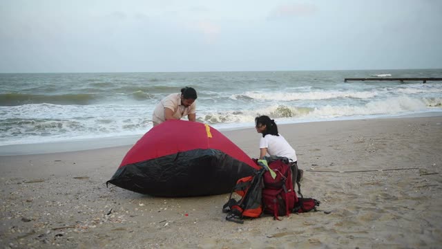 一男一女在海滩上准备帐篷视频下载