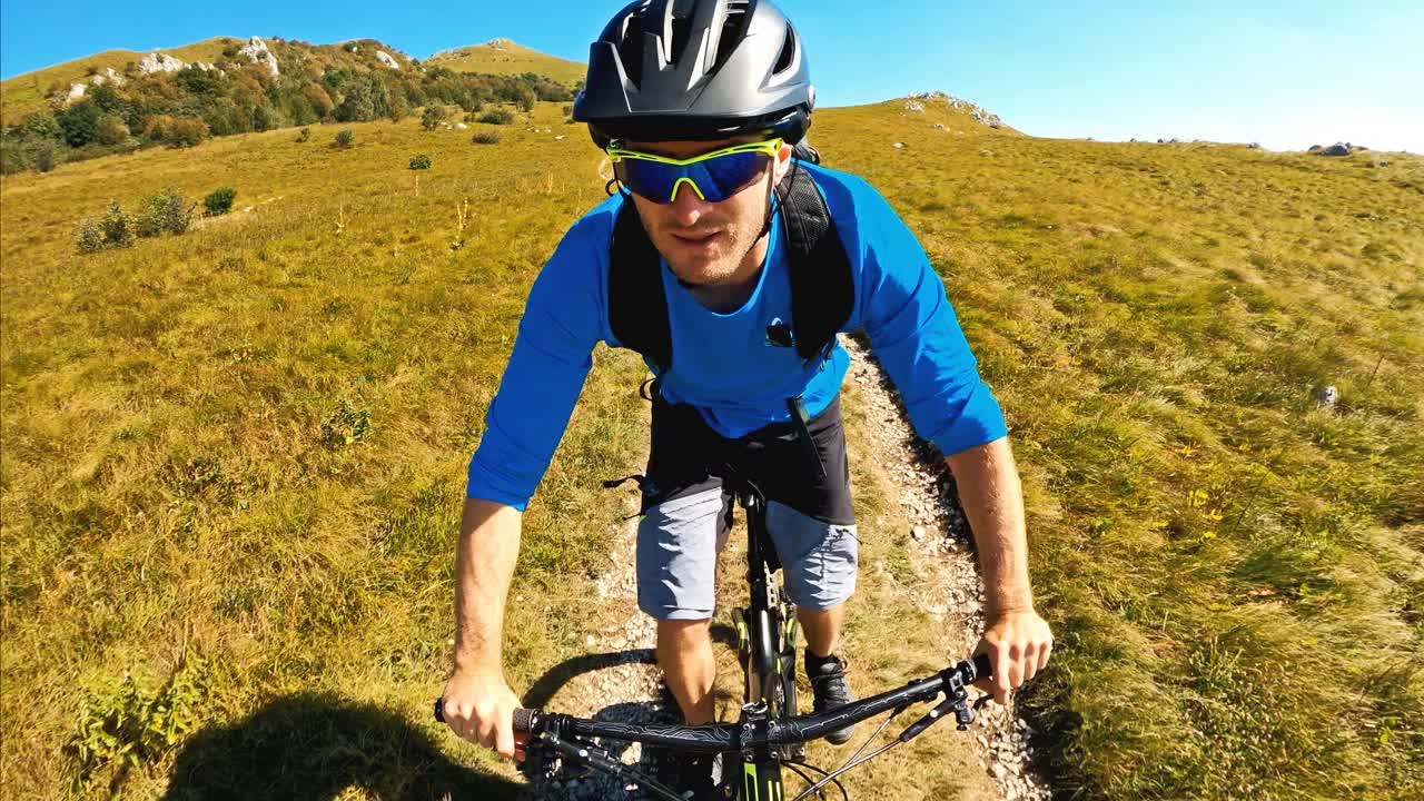 在一个阳光明媚的日子里，山地自行车手在岩石山脉上骑下坡视频下载