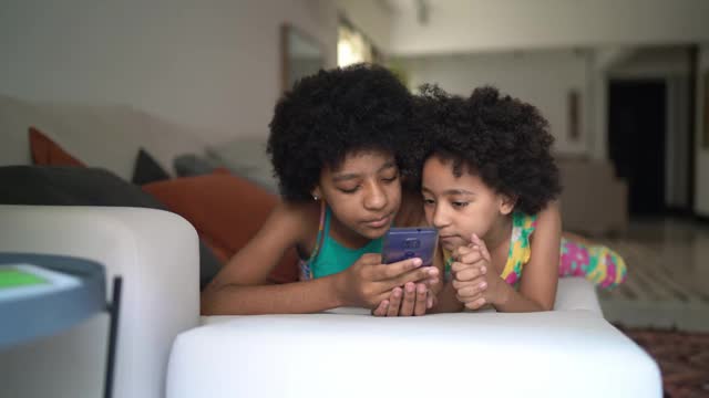 姐妹们一起躺在家里的沙发上使用智能手机视频素材