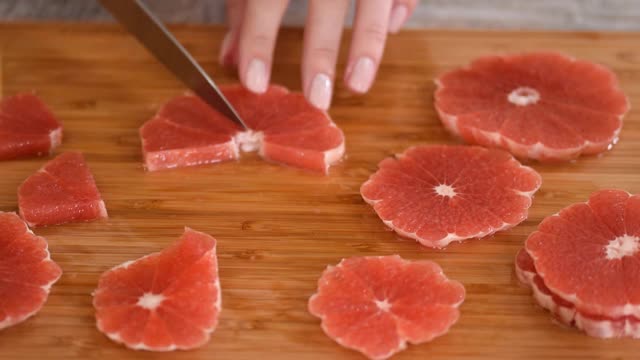 专业厨师用刀将熟透多汁的葡萄柚切成片，准备蔬菜水果沙拉。在家庭厨房准备午餐沙拉的原料视频素材