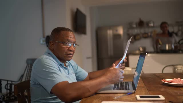 老年人用笔记本电脑支付账单或处理家庭财务视频素材