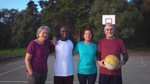 一群老年人在户外篮球场上拥抱抱着篮球视频下载