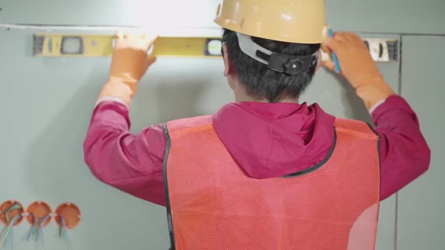 一位男性电工正在大楼里安装电气系统。视频素材