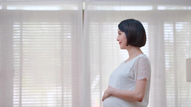亚洲男人或丈夫带来一杯牛奶给他怀孕的妻子，然后她喝了，在家里看起来很开心视频素材
