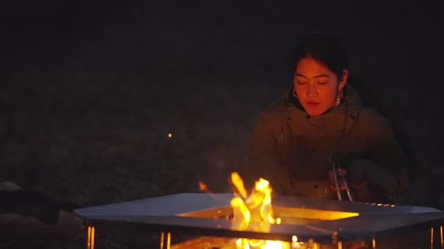 年轻女子在冬天的营火上暖手视频素材