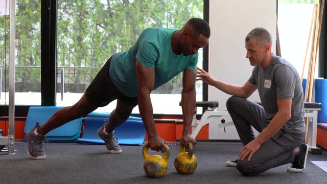 在健身房与私人教练进行运动训练视频下载