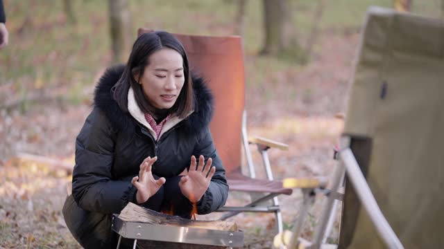 年轻女子在冬天的营火上暖手视频素材