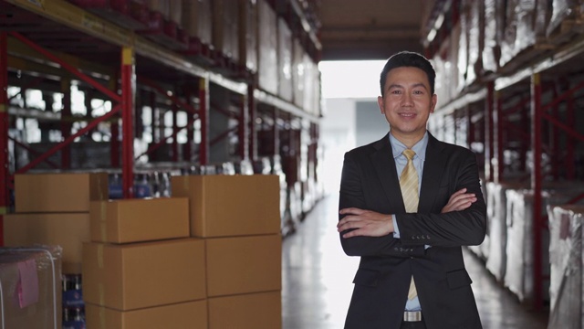 穿着西装的亚洲商人的肖像与库存货架在仓库视频购买
