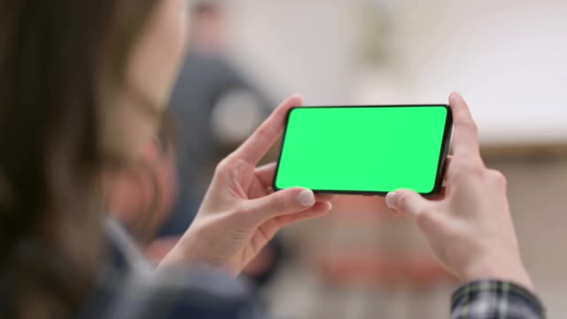 女性在看绿色按键屏幕的智能手机视频素材