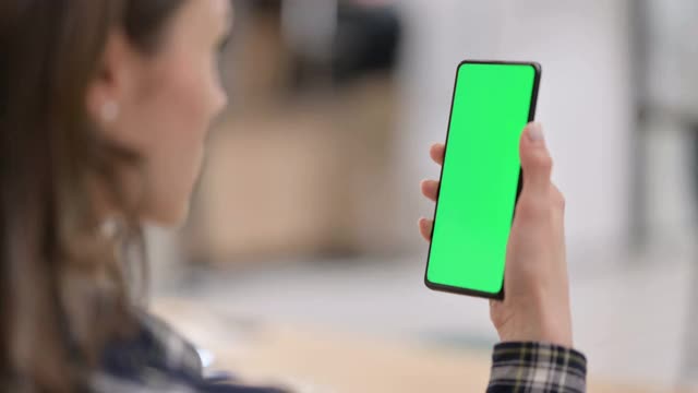 女性在看绿色按键屏幕的智能手机视频素材