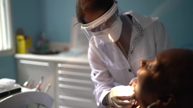牙医正在检查一位年长妇女的牙齿，她正坐在牙医椅上视频素材