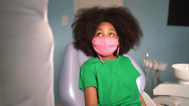 女孩在牙医的椅子上取下防护面罩视频素材