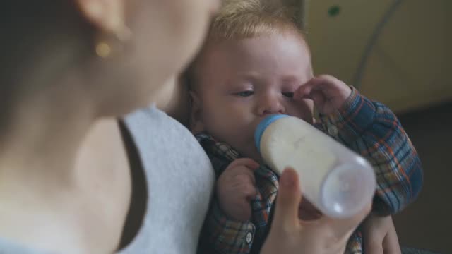 快乐的妈妈岩石儿子吃牛奶混合在宽敞的房间视频下载