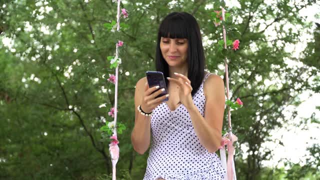 一名年轻女子使用手机，通过智能手机在社交网络上创建用户界面——点赞、关注者、评论视频下载