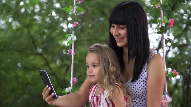 一个年轻可爱的小女孩和一个孩子与智能手机互动，在手机屏幕上输入文本，社交网络图标，同样数量的用户迅速增加视频素材