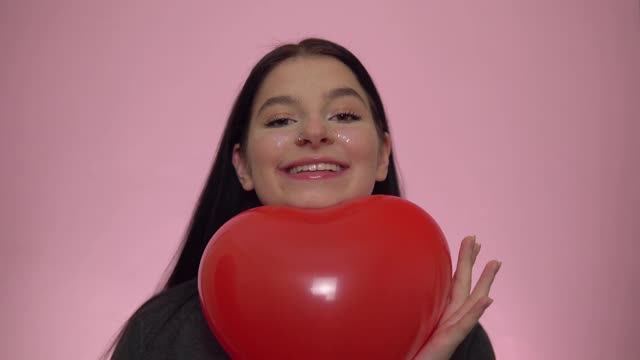 快乐微笑的女人捧着气球的心。情人节庆祝活动。视频素材