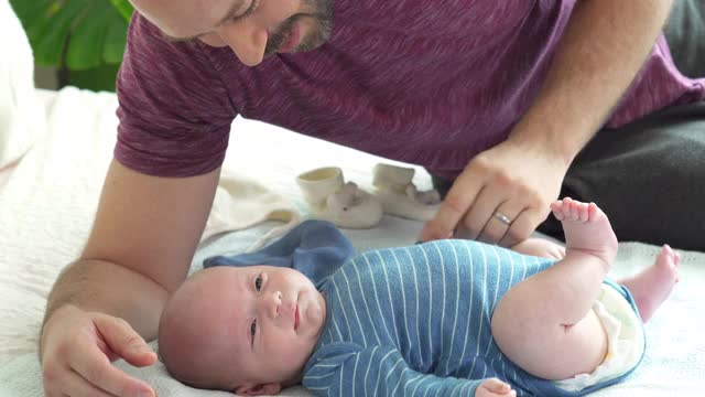 一位白人父亲在床上抱着并亲吻新生儿子的手视频素材