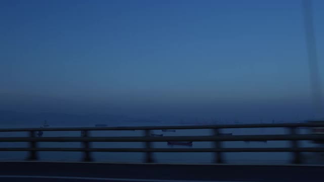 在韩国全罗南道丽水寺行驶的汽车上可以看到海景，货船和李新善大桥视频下载