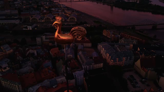 在美丽的里加老城，空中环绕着金色的气象公鸡飞行，在令人惊叹的日出空中视频下载