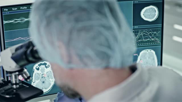 科学家在显微镜。电脑屏幕上的脑电波扫描研究视频素材