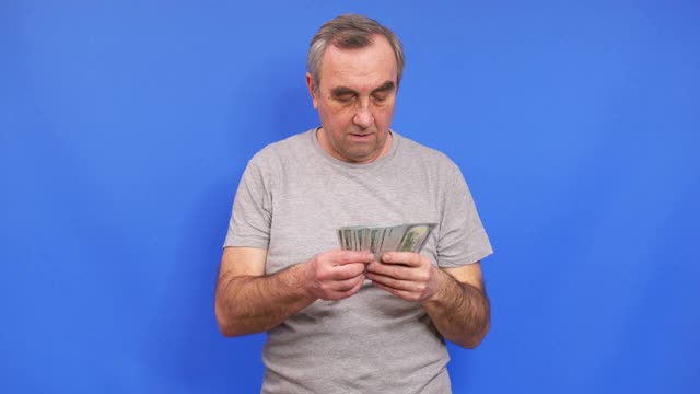 快乐的老人拿着一捆现金美元。视频素材