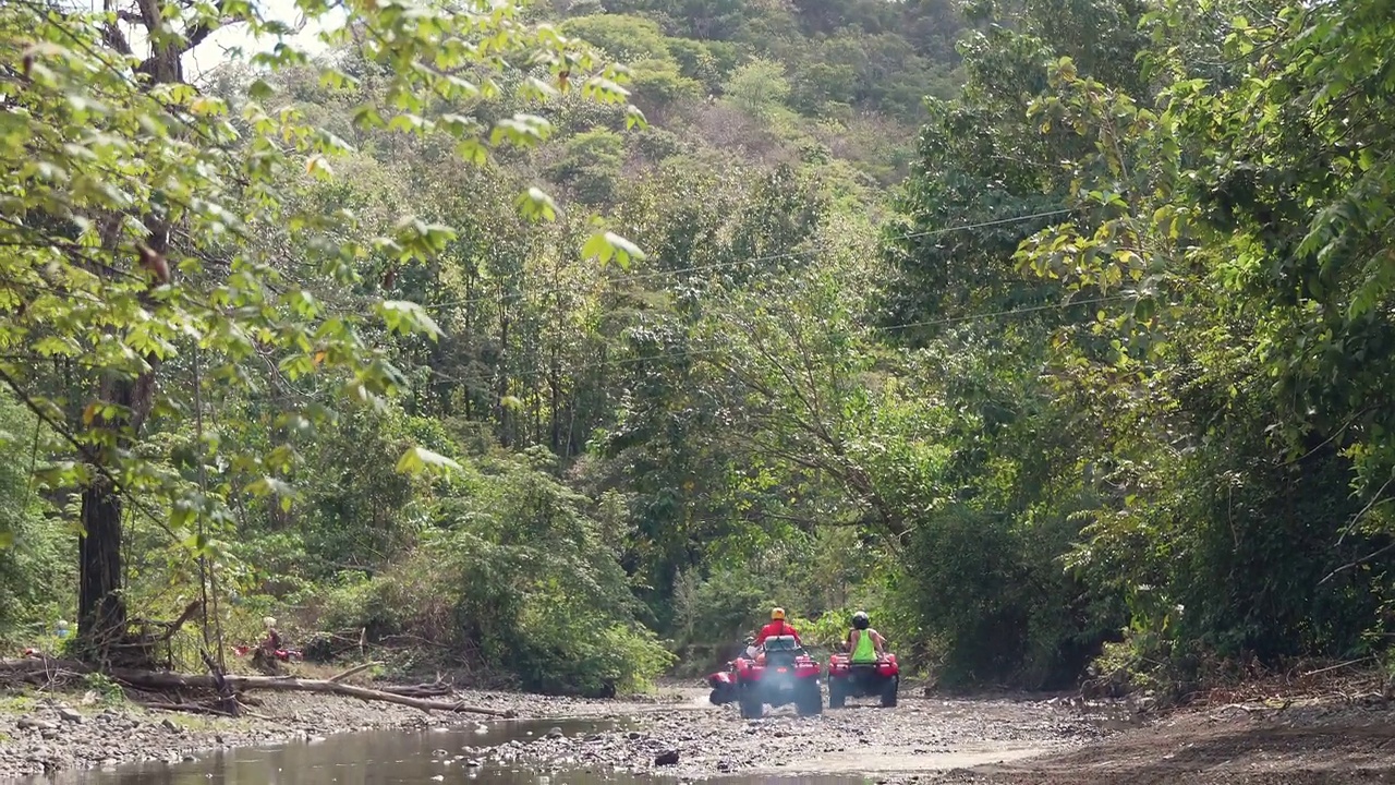 一群游客开着四轮自行车穿过哥斯达黎加的一条小溪视频素材