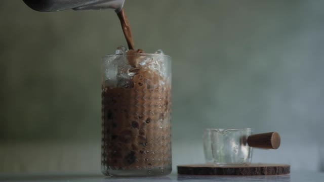 将茶点摩卡咖啡加冰倒入玻璃杯中。慢动作视频素材