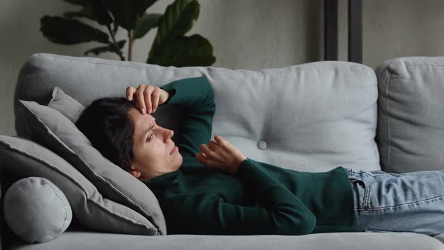 女人躺在沙发上，沉浸在悲伤的个人问题中视频素材