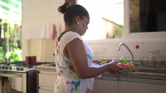 成熟的女人把沙拉碗放在家里的冰箱里视频下载