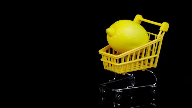 黑色背景下黄色购物篮里的柠檬。旋转视频下载