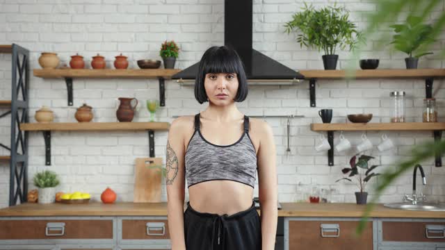 一个穿着运动服有纹身的女人在家里练习瑜伽视频下载