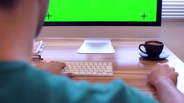 一个人在桌子上工作，咖啡在屏幕前与绿色屏幕背景视频下载